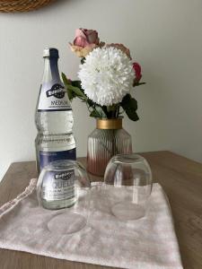 a bottle of water and a vase with flowers on a table at Waldblick Gästezimmer in Sonnenbühl