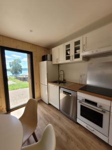 eine Küche mit weißen Geräten sowie einem Tisch und Stühlen in der Unterkunft Maison bord du Lac des Settons in Montsauche-les-Settons