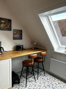 Una cocina con una encimera con dos taburetes y una ventana. en Wohnung mit Kahnstelle, en Maasholm