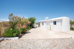 a small white building with a fence and flowers at PARADISE SEA HOUSE a in Haraki +7 photos