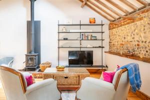 un salon avec deux chaises et une télévision dans l'établissement Bellas Barn by Big Skies Cottages, à Weybourne