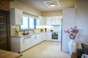 a kitchen with white cabinets and a vase of flowers at Secluded Luxury Villa w Jacuzzi & Stunning Views in Kali Limenes