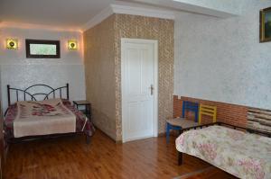 a bedroom with two beds and a door and a chair at TJ Guest House in Makhinjauri