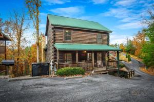 a wooden house with a green roof and a driveway at Blue Ridge Retreat in Pigeon Forge