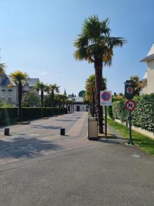 a street with palm trees and signs on a sidewalk at HAVRE MARIN DU CENTRE VILLE lumineux, spacieux à 5 min de la plage in Dinard +8 photos