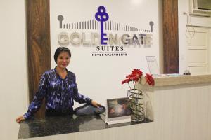 a woman standing behind a counter with a vase of flowers at Golden Gate Suites in Dumaguete