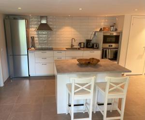 a kitchen with a counter and two stools in it at Plomben C in Båstad