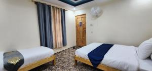 een kleine slaapkamer met twee bedden en een raam bij Adventure Sarai Skardu in Skardu
