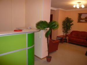 a lobby with a green counter and a palm tree at Viktoria Hotel in Cherepovets