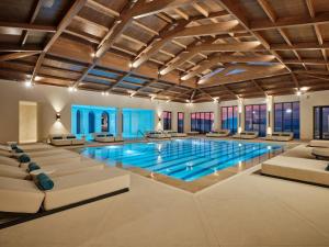 Una gran piscina con sofás y sillas en un edificio. en Oros Luxury Beach Resort, en Georgioupolis