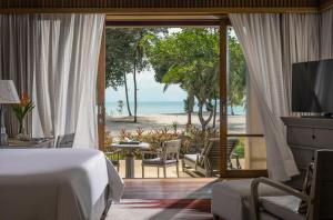 a bedroom with a bed and a view of the beach at Four Seasons Resort Langkawi in Tanjung Rhu