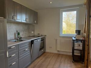 a kitchen with gray cabinets and a sink and a window at Ferienhaus Wäschegrund in Sankt Andreasberg