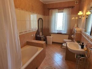 a bathroom with a tub and a toilet and a sink at Mysi Dwór Pokoje Gościnne Lublewo in Lublewo