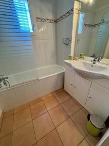a bathroom with a tub and a sink and a bath tub at Appartement - 4 chambres - piscine collective- place de parking privée (garage) in Saintes-Maries-de-la-Mer