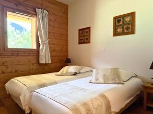 two beds in a bedroom with a window at Mouflon, terrasse confort piscine, Spa in Champagny-en-Vanoise