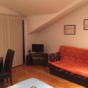 a living room with a red couch and a tv at Apartment The Royal Pg in Podgorica