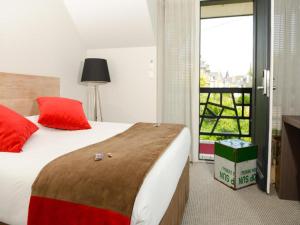 a bedroom with a bed with red pillows and a window at Hôtel Ar Iniz in Saint Malo