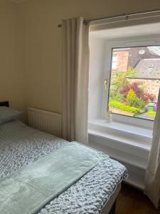 Un dormitorio con una cama al lado de una ventana. en Kirriemuir entire 3 bed house, en Moffat