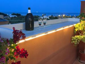 a bottle of wine and two wine glasses on a ledge at Baires&Blo Ático duplex, Terraza chillout exclusiva y vistas al mar in Benicarló