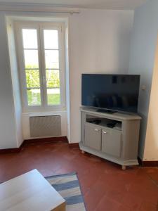 a living room with a flat screen tv and a window at Aux Petits Bonheurs in Grandcamp-Maisy