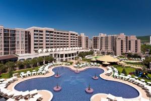a resort with a large pool and chairs and buildings at SoloApartment in Sunny Beach