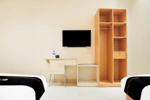 a room with a desk and a television on a wall at Dancenter KR Hotel in Palembang