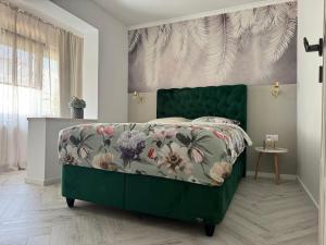 1 Schlafzimmer mit einem grünen Bett und einer Blumenbettdecke in der Unterkunft Apartament Victoria in Tîrnăveni