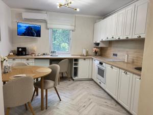 eine Küche mit weißen Schränken und einem Tisch mit Stühlen in der Unterkunft Apartament Victoria in Tîrnăveni