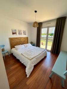 ein Schlafzimmer mit einem großen Bett und einem großen Fenster in der Unterkunft La Maison Bleue in Saint-Avé
