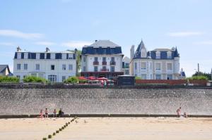 a group of people standing on a beach next to buildings at Hôtel Ar Iniz in Saint Malo