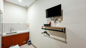 a bathroom with a sink and a tv on a wall at Tuwin Guest House Syariah in Yogyakarta +49 photos