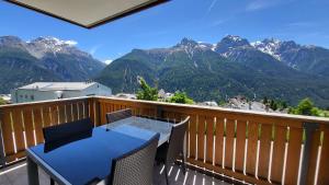 a table and chairs on a balcony with mountains at Chasa Scandella - Apartment Carl in Sent