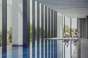 two women sitting in chairs next to a swimming pool at InterContinental Tashkent by IHG in Tashkent