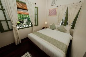 a bedroom with a white bed and a window at Barn Laos Luangprabang Heritage in Luang Prabang