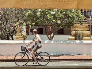 a man riding a bike down the street at Barn Laos Luangprabang Heritage in Luang Prabang