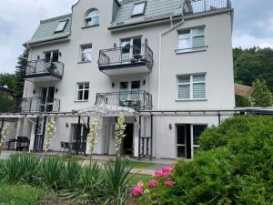 a white house with balconies and flowers at Apartament od rzeki nr 7 in Gdynia