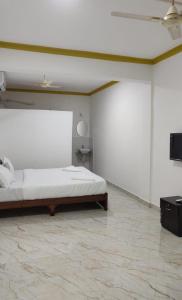 a white bedroom with a bed and a flat screen tv at cbc joy resort in Calangute