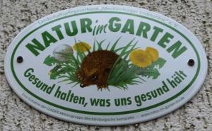 a sign for a garden with a mouse in the grass at Fewos Storchenhof am Kummerower See in Meesiger