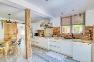 a kitchen with white cabinets and a wooden table at La Cabane O Rêves - Chalet Cosy - Pleine nature in Lagnieu