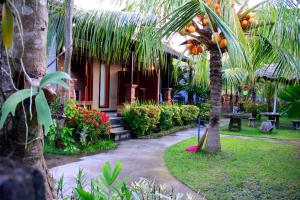 a garden with a house with a palm tree and flowers at Gara menjangan homestay in Banyuwedang