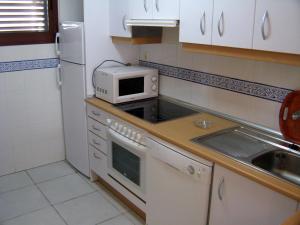 a kitchen with a microwave and a stove top oven at Apartamento VenAVera Playa Jardines de Nuevo Vera L1-2E Ático Primera Línea WIFI in Vera