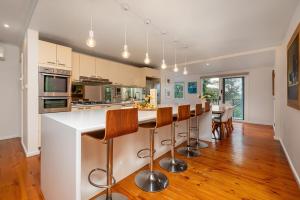 a kitchen with a island with bar stools at Cosy Coastal Beach Cottage in Rye in Rye