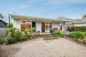a house with a porch with a couch in the yard at Cosy Coastal Beach Cottage in Rye in Rye