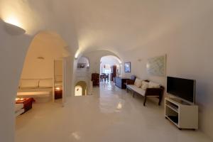 a living room with a couch and a tv at White House Villa in Oia