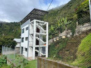Un edificio blanco detrás de una valla junto a una colina. en Moon View Suite, en Baños