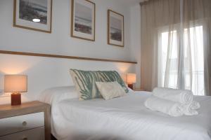 ein Schlafzimmer mit einem weißen Bett mit Handtüchern darauf in der Unterkunft Apartamento Sol de Maro in Maro