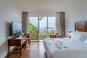 una camera d'albergo con un letto, una scrivania e una televisione di Hulhule Island Hotel- Private Beach Access & Airport Pick-up and Drop a Città di Malé