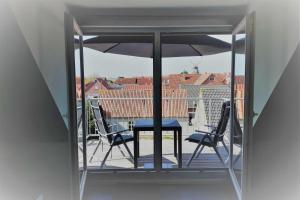 une table et des chaises sur un balcon avec un parasol dans l'établissement Ferienwohnung Claudia, à Carolinensiel