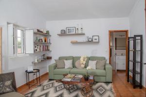 a living room with a green couch and a table at Casas Porta Alegre in Portalegre