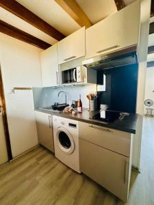 a kitchen with a sink and a washing machine at Le cosy vue mer in Fleury